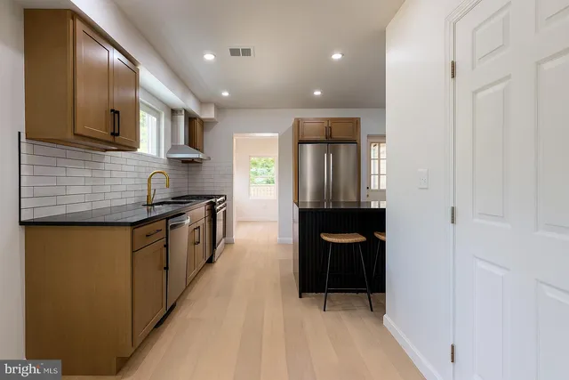 a kitchen with stainless steel appliances granite countertop a refrigerator a sink dishwasher and wooden cabinets with wooden floor