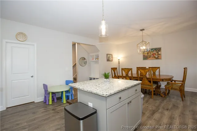 a kitchen with a refrigerator a stove a sink and a dining table with wooden floor