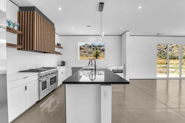 a kitchen with stainless steel appliances granite countertop a stove a sink and a microwave