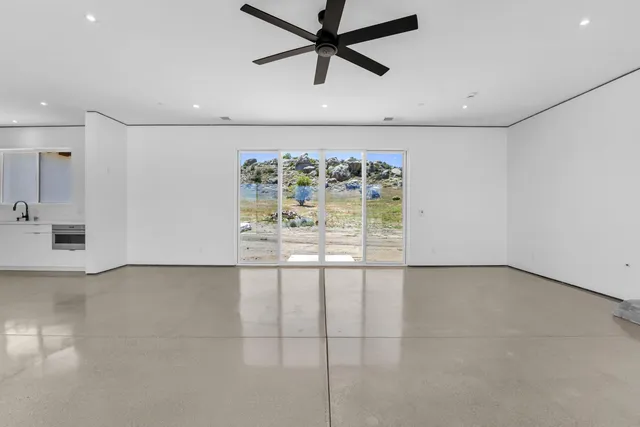 a view of an empty room with a window and a ceiling fan