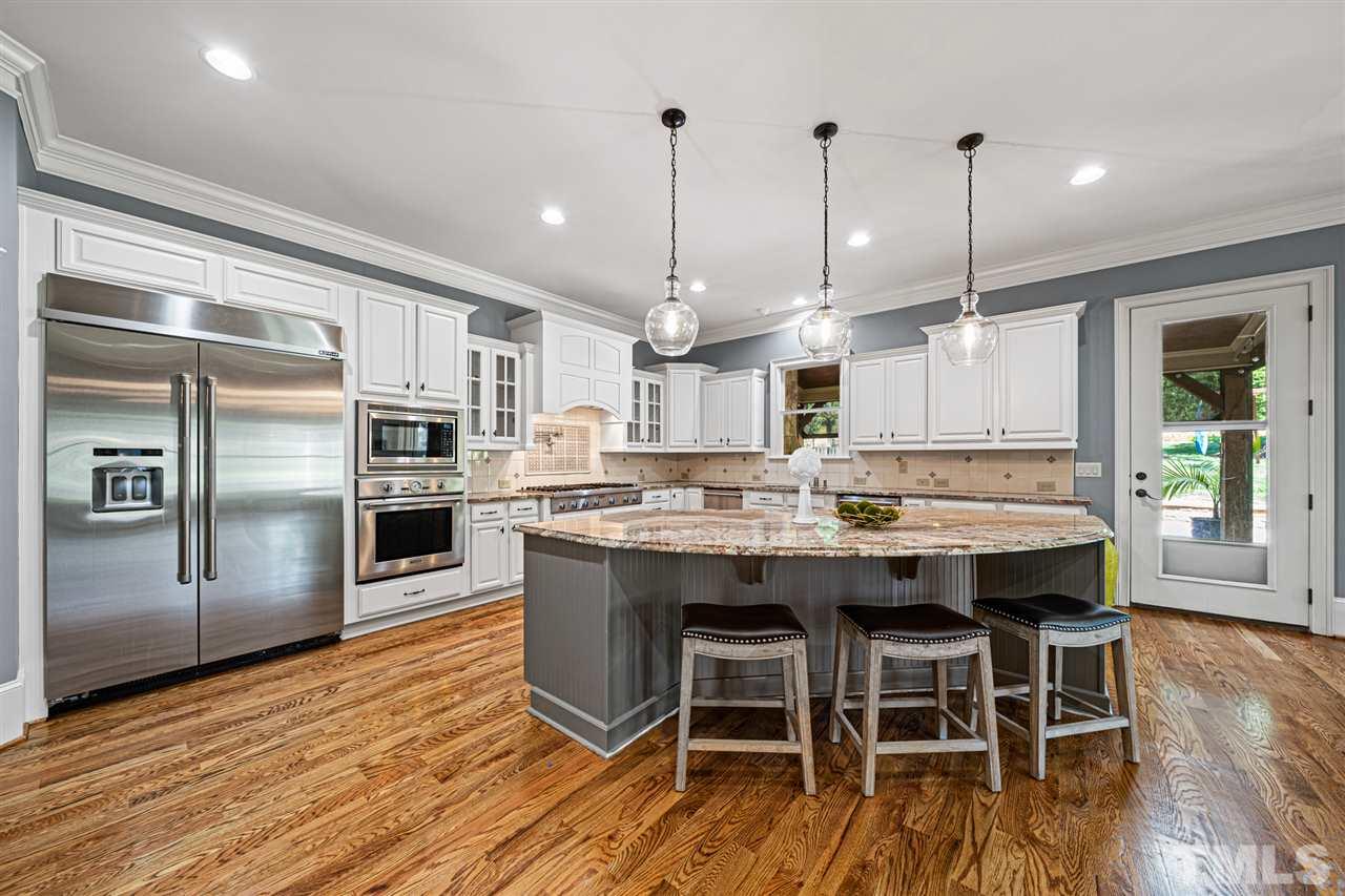 12515 Tuscan Lake Road Raleigh, NC 27613 - Photo 16 of 30 a kitchen with stainless steel appliances granite countertop a kitchen island hardwood floor and a sink