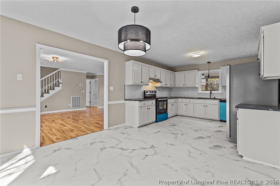 5356 Wade-Stedman Road Wade, NC 28395 - Photo 16 of 38 a kitchen with stainless steel appliances kitchen island granite countertop a sink a stove and refrigerator