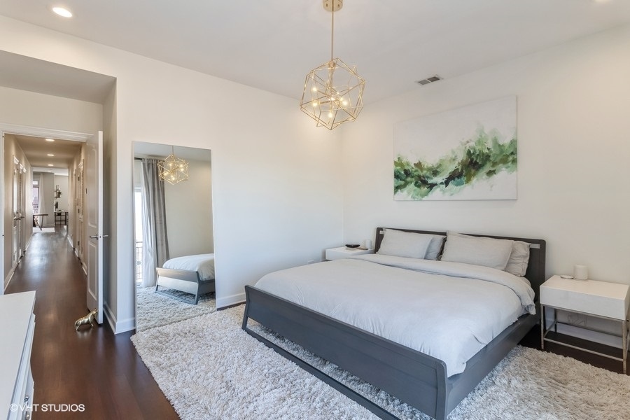 2122 West Rice Street, Unit 4 Chicago, IL 60622 - Photo 9 of 22 a spacious bedroom with a bed and a chandelier