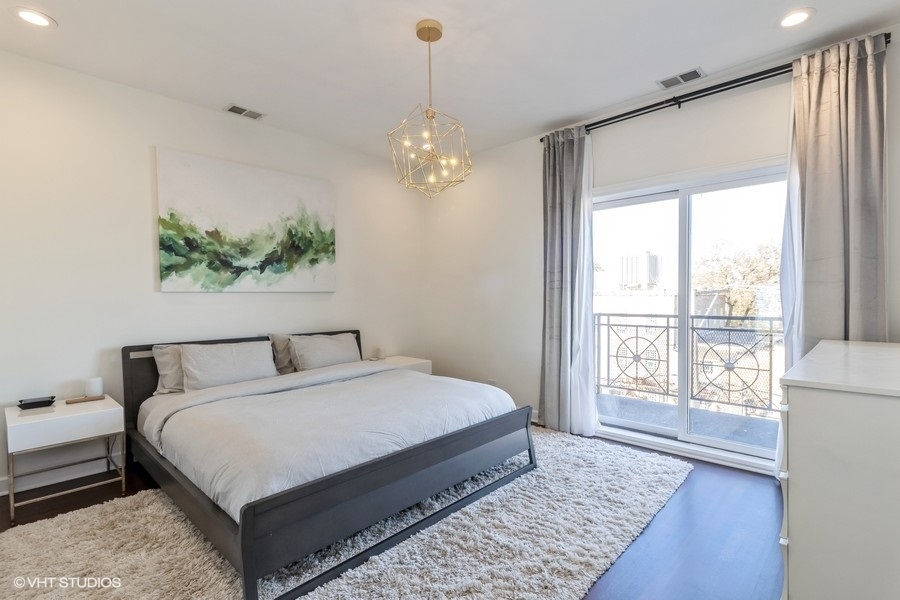 2122 West Rice Street, Unit 4 Chicago, IL 60622 - Photo 10 of 22 a bedroom with a large bed and a chandelier
