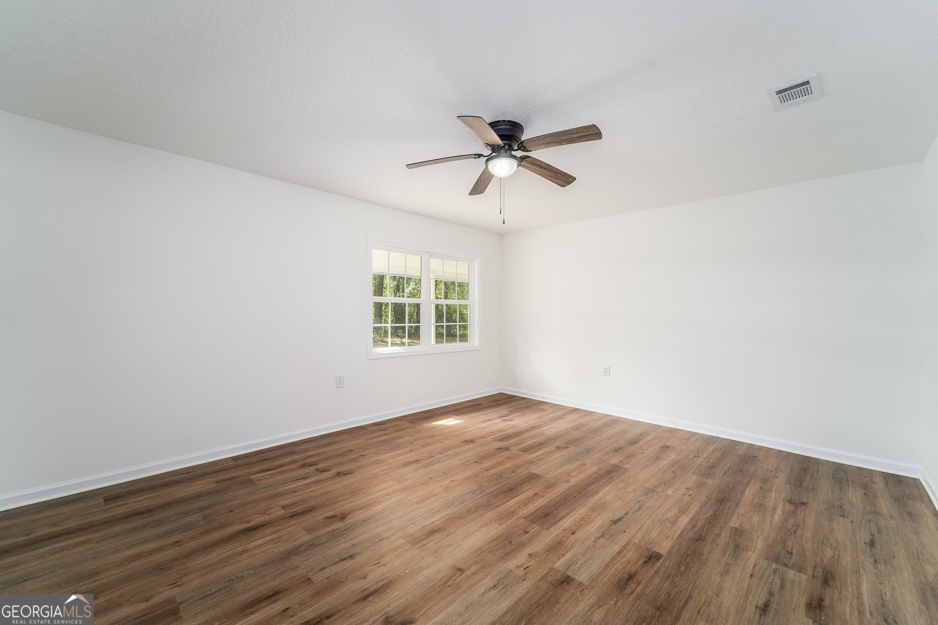 3551 Cason Road Blackshear, GA 31516 - Photo 11 of 24 an empty room with wooden floor fan and windows