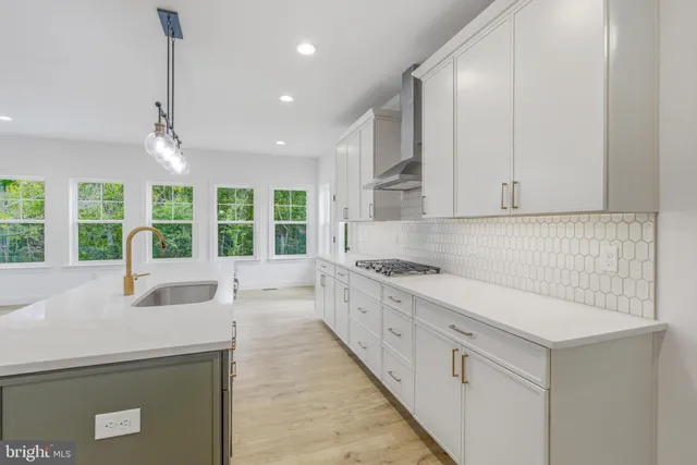 a large white kitchen with granite countertop a sink window and cabinets