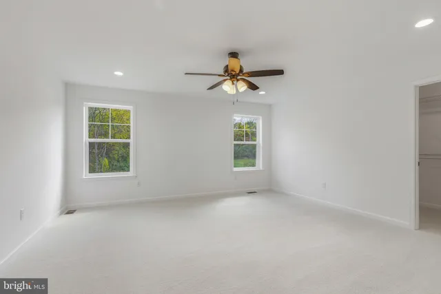 an empty room with windows and chandelier fan