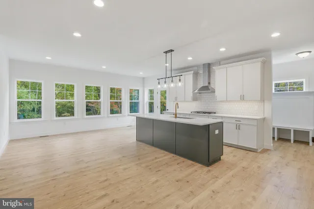 a large kitchen with kitchen island a large counter top space a sink stainless steel appliances and cabinets