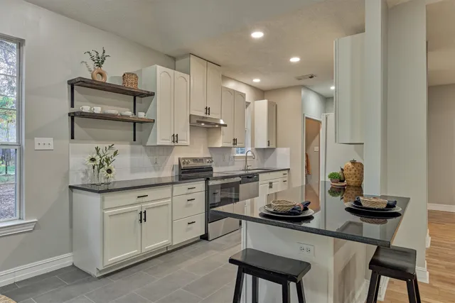 a kitchen with white cabinets and chairs