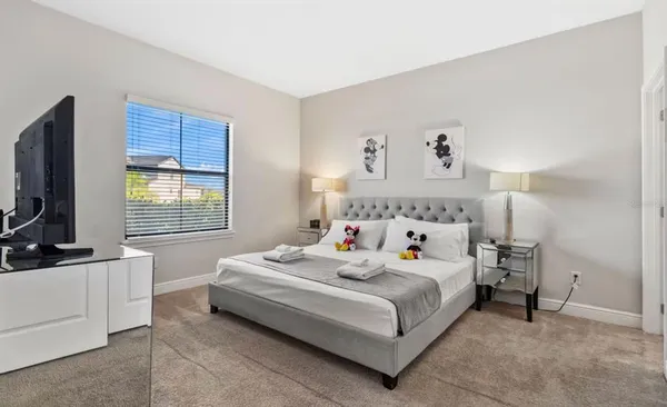 a bedroom with a bed and a flat tv screen on the dresser