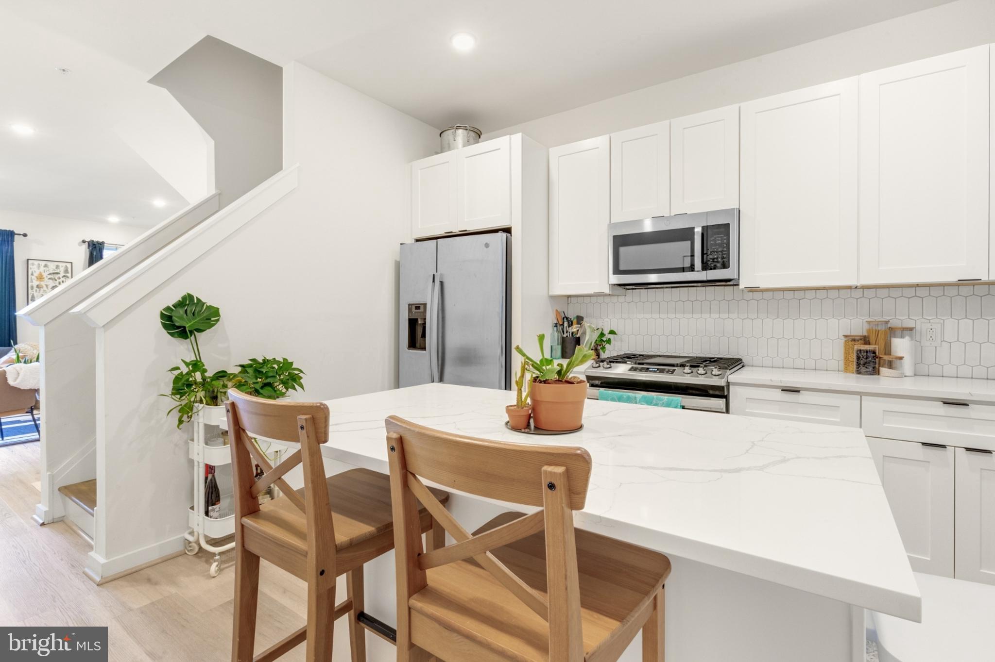 2212 North Front Street, Unit 5 Philadelphia, PA 19133 - Photo 8 of 25 a kitchen with stainless steel appliances kitchen island granite countertop a table chairs and a refrigerator
