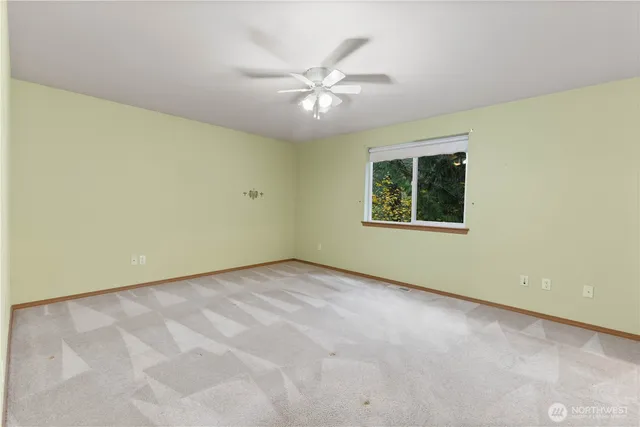 an empty room with a ceiling fan and window