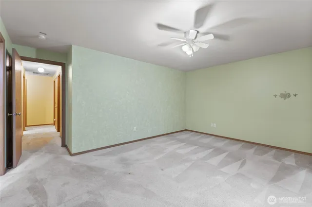 an empty room with a ceiling fan and carpet