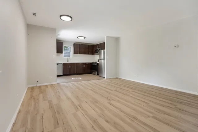 a view of a room with wooden floor and kitchen