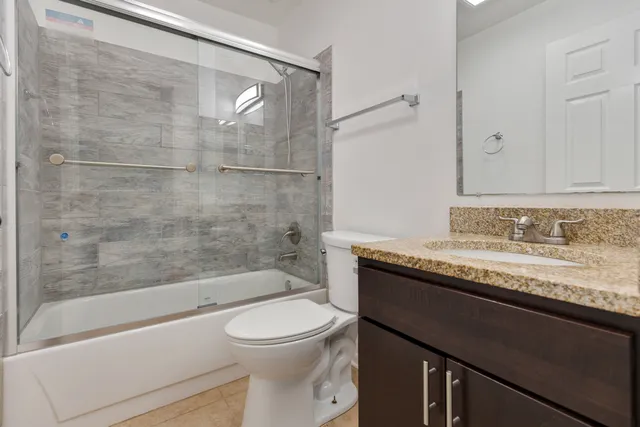 a bathroom with a granite countertop sink a toilet and bathtub