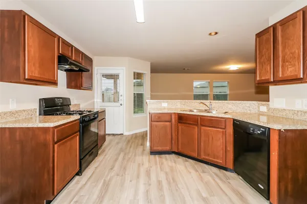 a kitchen with stainless steel appliances granite countertop wooden cabinets a sink dishwasher a stove and a refrigerator
