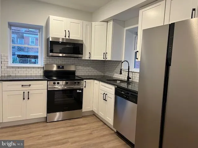 a kitchen with stainless steel appliances granite countertop a stove a refrigerator and a microwave