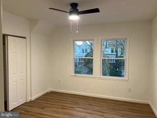 an empty room with wooden floor chandelier fan and windows