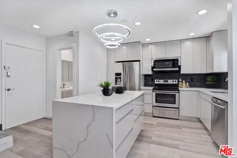 a kitchen with kitchen island white cabinets and appliances