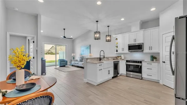 a kitchen with stainless steel appliances granite countertop a refrigerator a sink a stove and a oven with wooden floor