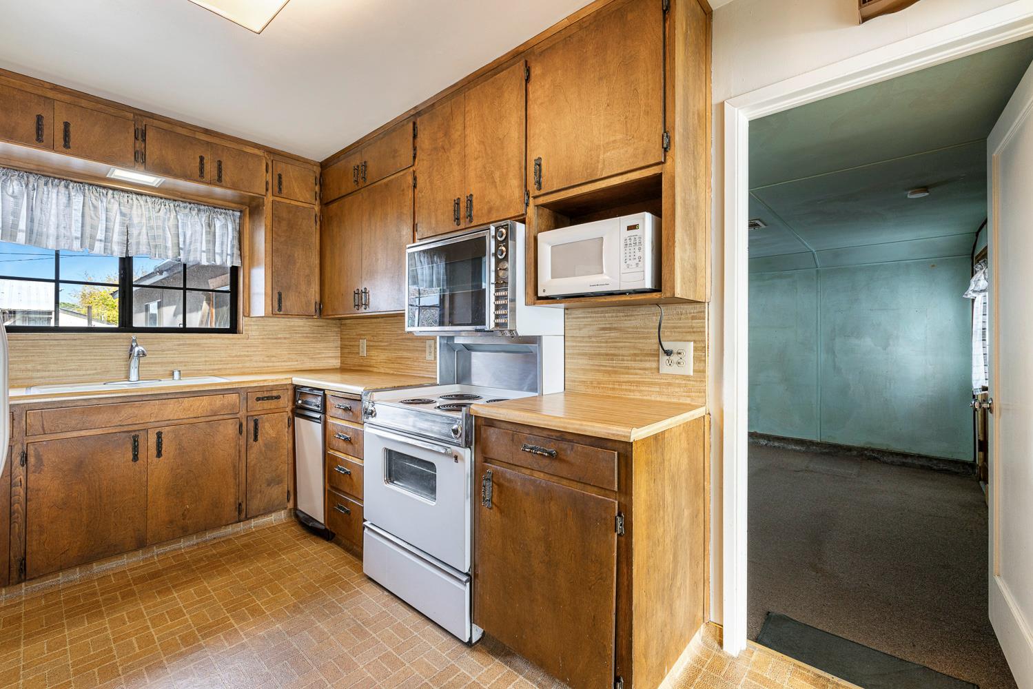 183 Harrison Street Coalinga, CA 93210 - Photo 15 of 45 a kitchen with a sink a stove and cabinets