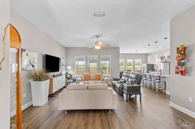 a kitchen with stainless steel appliances granite countertop a refrigerator a stove a sink a dining table and chairs with wooden floor