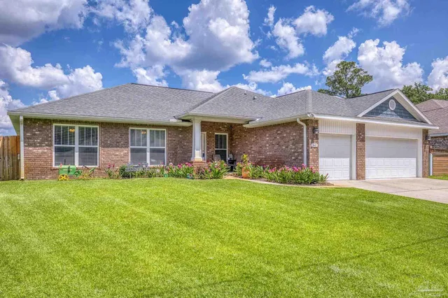 a view of a brick house with a big yard and large trees