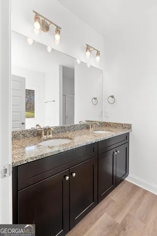 a bathroom with a granite countertop double vanity sink and a mirror
