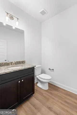 a bathroom with a granite countertop toilet and a sink