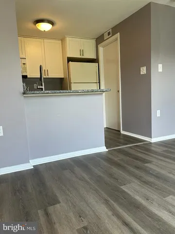 an empty room with wooden floor and a sink