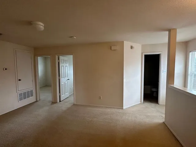 a view of an empty room with closet and a window