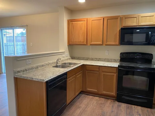 a kitchen with granite countertop a sink stove and microwave
