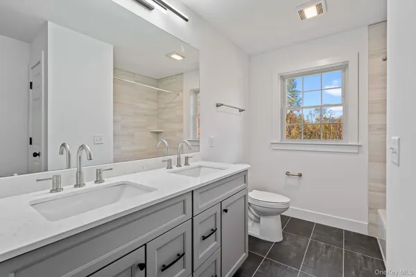 a bathroom with a double vanity sink a toilet and a mirror