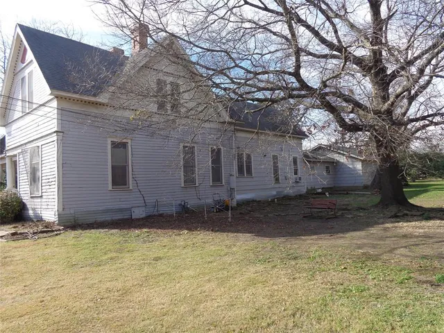 a view of a house with a yard and large tree
