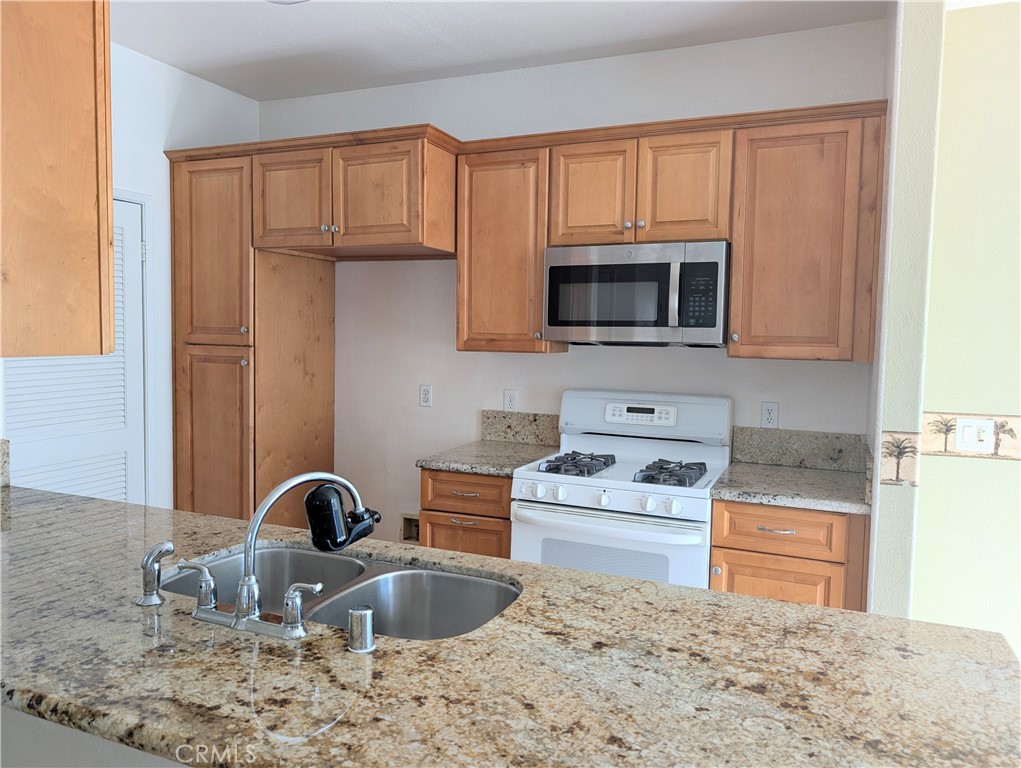 13133 Le Parc, Unit 1009 Chino Hills, CA 91709 - Photo 17 of 21 a kitchen with granite countertop a stove a sink and a microwave