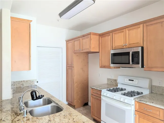 a kitchen with granite countertop a sink stove and refrigerator