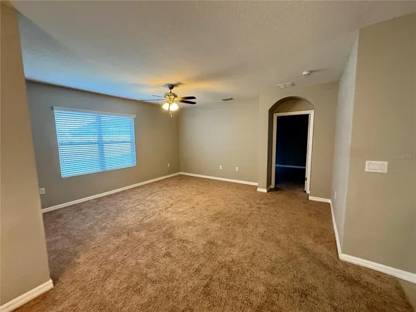 an empty room with windows and chandelier fan