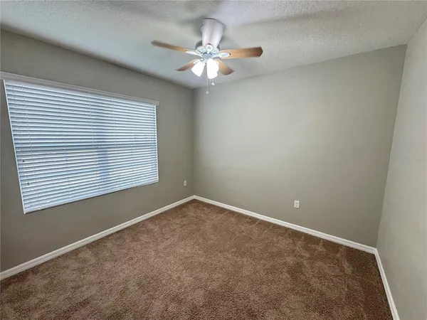 an empty room with a window and a ceiling fan