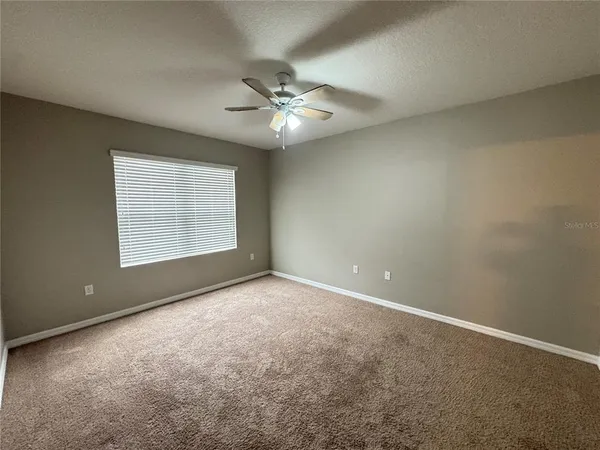an empty room with windows and fan
