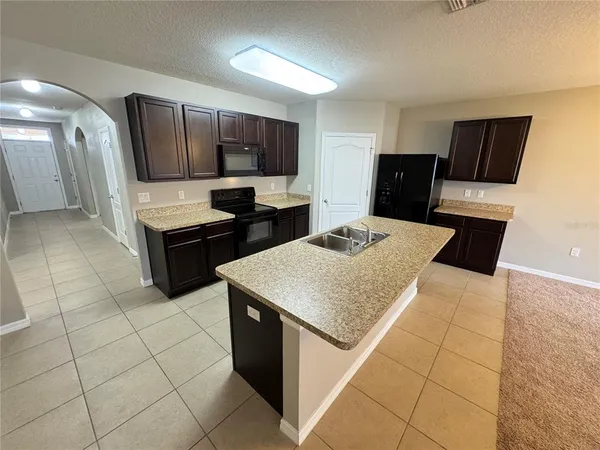 a kitchen with stainless steel appliances a sink a stove a microwave a counter top space and cabinets