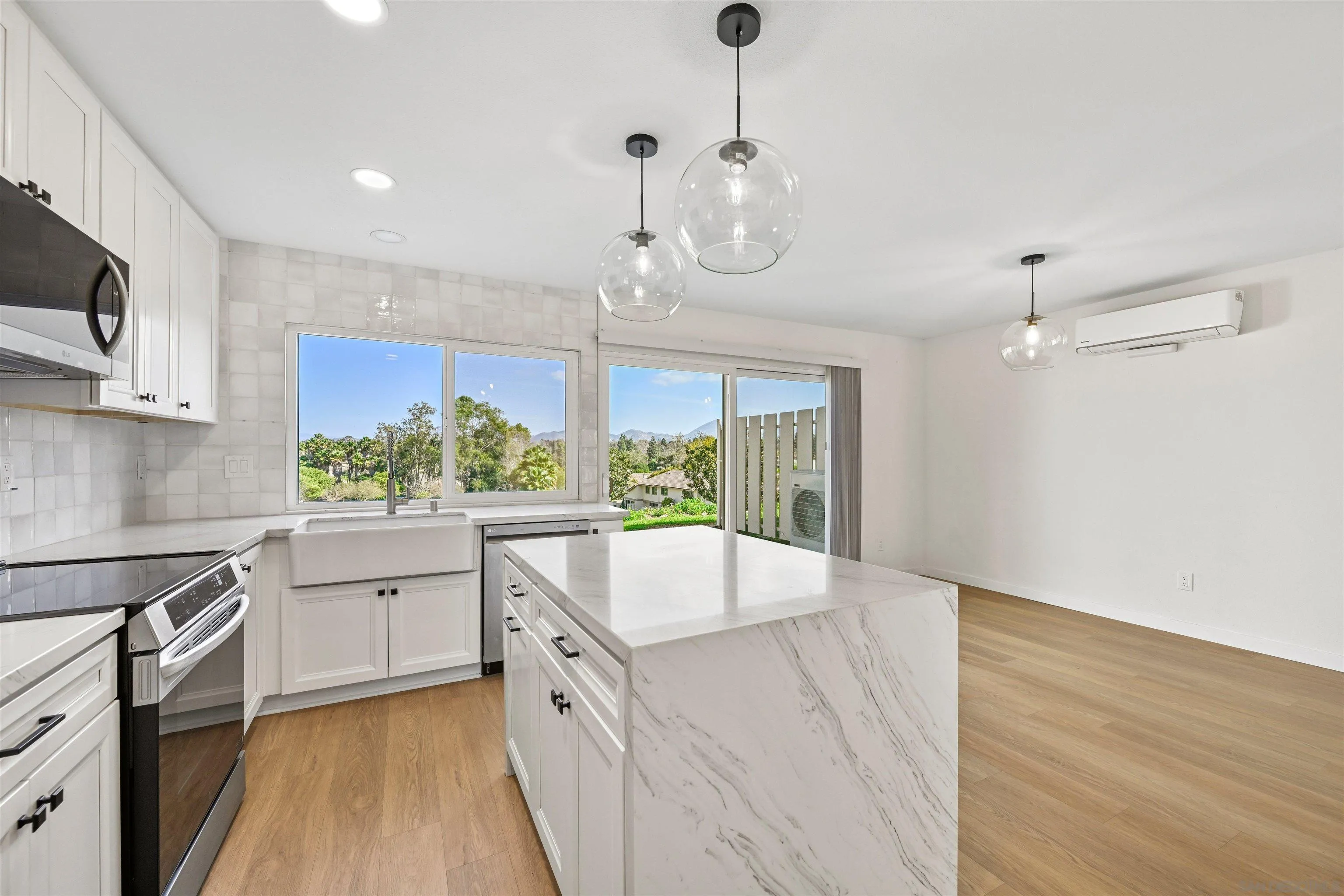 11218 Poblado Road San Diego, CA 92127 - Photo 11 of 35 a large kitchen with stainless steel appliances a white stove top oven a sink dishwasher and a dining table with wooden floor