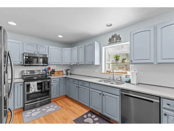 a kitchen with stainless steel appliances kitchen island granite countertop a dining table chairs and white cabinets