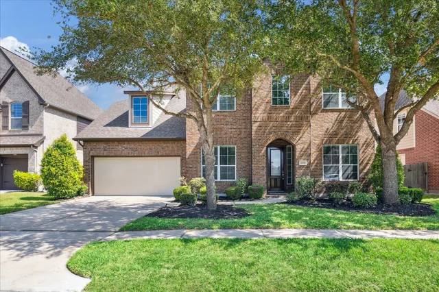 a front view of a house with garden and trees