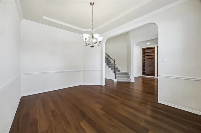 a view of a livingroom with wooden floor staircase and a kitchen space