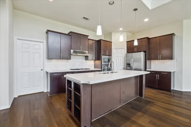 a kitchen with kitchen island a sink stainless steel appliances and cabinets
