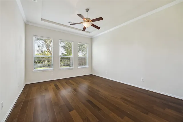 an empty room with wooden floor fan and windows