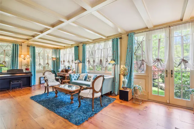 a living room with furniture large windows and wooden floor