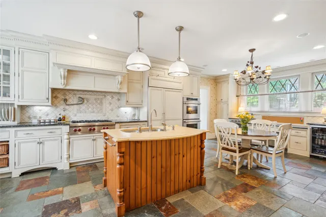 a open kitchen with stainless steel appliances granite countertop a stove a refrigerator a kitchen island a dining table and chairs