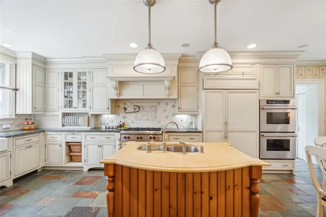 a kitchen with kitchen island granite countertop a sink a stove and a wooden floors
