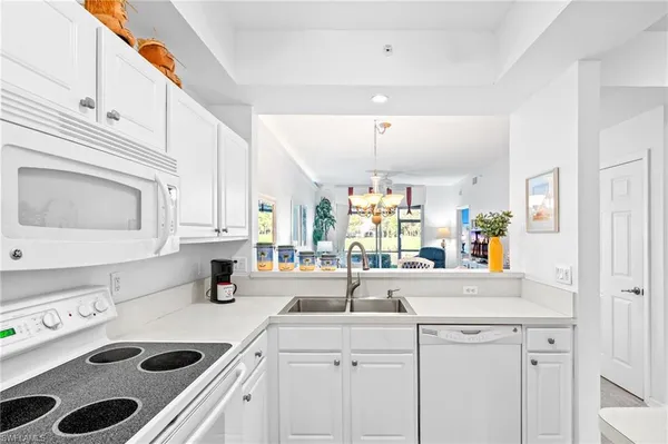 a kitchen with kitchen island white cabinets and white appliances